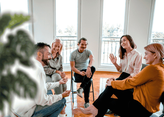 Group of people sitting and chatting happily during an acceptance and commitment therapy session