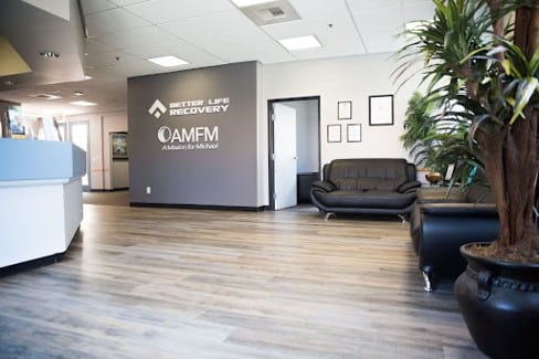 The modern, clean lobby of a recovery facility featuring neutral tones and black leather seating.