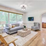 A bright, welcoming therapy office of AMFM with a gray sofa, a wingback chair, and large windows.
