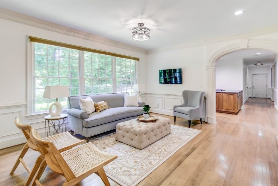 A bright, welcoming therapy office of AMFM with a gray sofa, a wingback chair, and large windows.