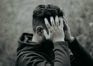 Man with his head in his hands, struggling due to mental health stigma
