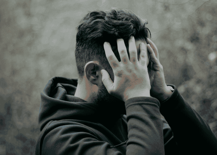 Man with his head in his hands, struggling due to mental health stigma
