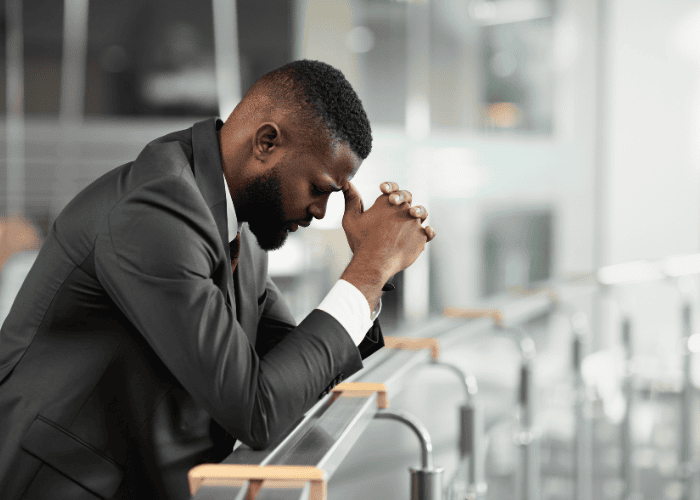 Man in suit resting his head on his hands while looking down
