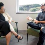 Man and woman sitting in chairs looking at each other during therapy session