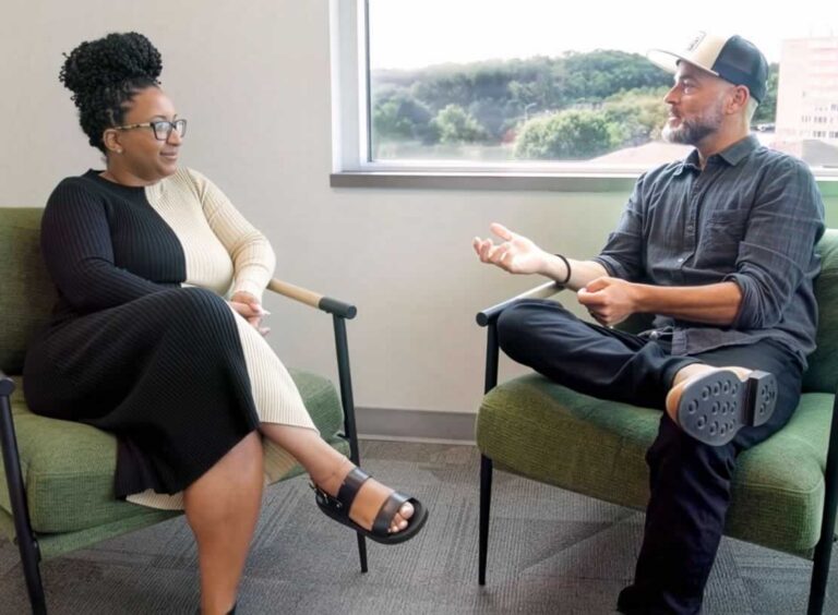 Man and woman sitting in chairs looking at each other during therapy session