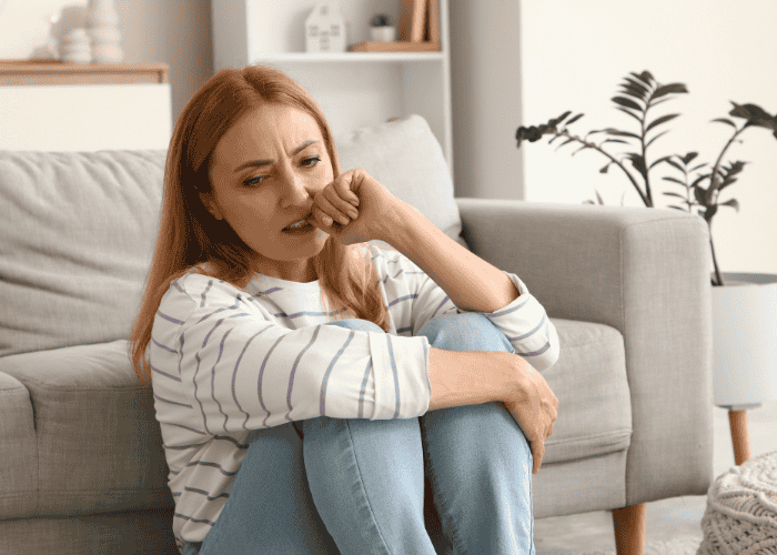 Woman sitting on the floor biting her nails due to political stress and anxiety