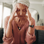 Woman sitting on the couch with her head in her hands due to stress and anxiety