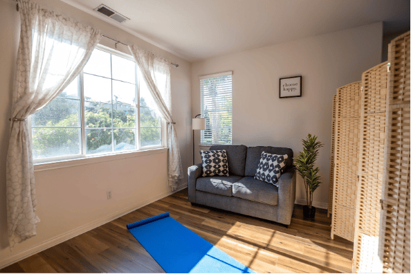 One of AMFM Mental Health Treatment facilities. with a comfortable sofa and a blue yoga mat for mindfulness practice to aid mental health recovery.