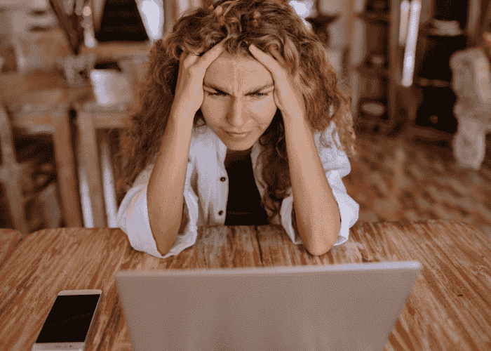 Woman looking frustrated at her laptop due to AI in mental health treatment