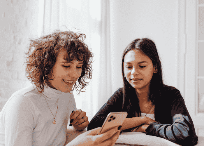 Two adult women looking at mental health apps on their phone