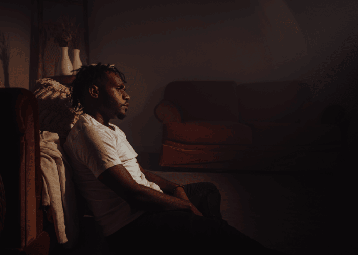 Man sitting in the dark struggling with mental health crisis warning signs