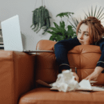 Woman leaning over her sofa looking at her laptop, dealing with burnout vs depression