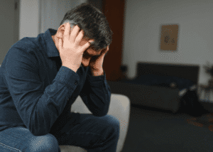 Man with his head in his hands struggling to achieve mental health stigma reduction