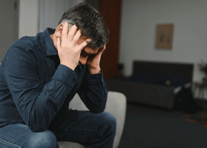 Man with his head in his hands struggling to achieve mental health stigma reduction