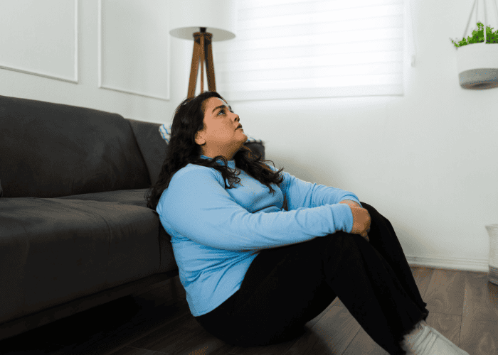 Woman sitting on the floor experiencing news anxiety