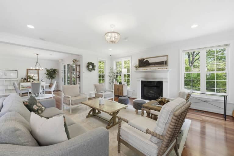 Bright living room with modern couch and chairs and large windows looking out at green trees