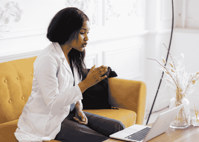Woman sitting on the couch using her laptop during virtual therapy