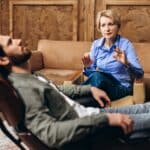 Man leaning back in chair during therapy appointment with female psychodynamic therapist at amfm