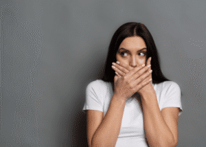 woman holding her hands over her mouth after hearing myths about tourette's