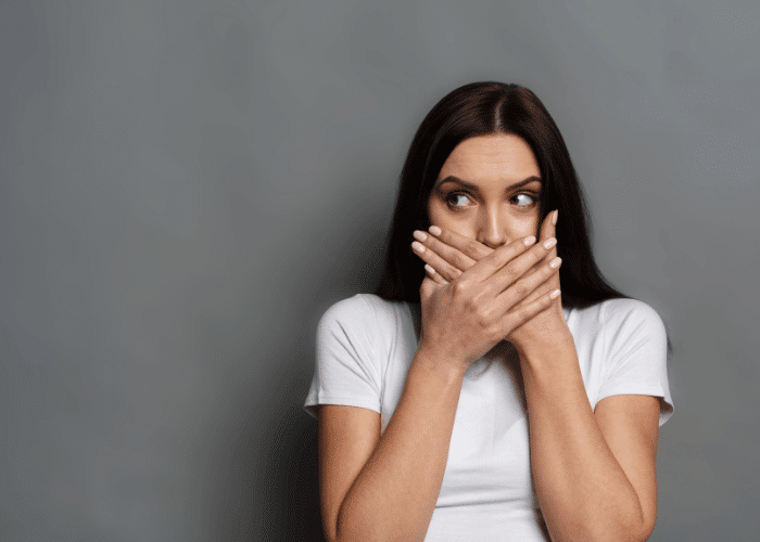 woman holding her hands over her mouth after hearing myths about tourette's