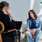 woman sitting on couch across from female therapist at amfm individual therapy session