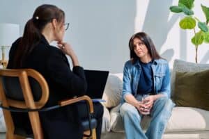 woman sitting on couch across from female therapist at amfm individual therapy session