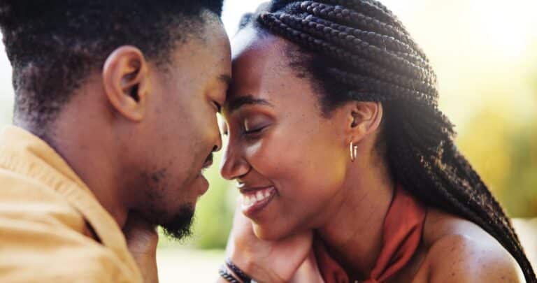 Male and female standing forehead to forehead smiling at each other in romantic way