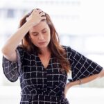 Woman looking frustrated with eyes closed and one hand on hip while other hand is on head